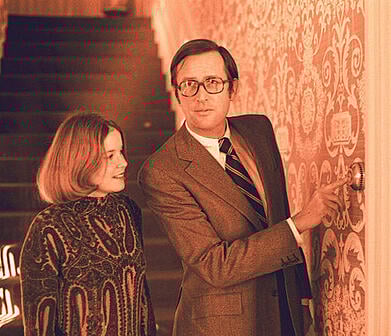 A man and woman look at a thermostat